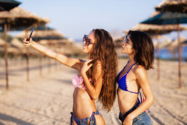 ragazze sexy che si divertono su una spiaggia - umbrella beach sex symbol white foto e immagini stock