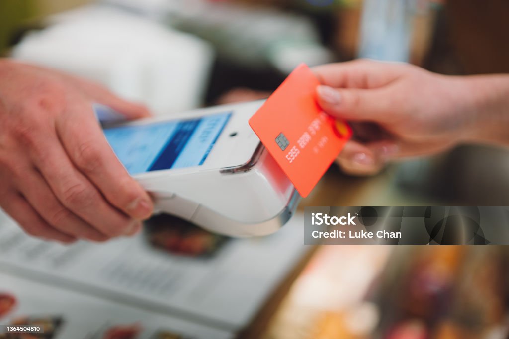 Asian beautiful woman paying a bill using contactless payment by smartphone. Close-up shot of wireless payment inside a restaurant. Credit Card Reader Stock Photo