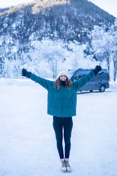 Photo of Young woman leaves vehicle on a snowy lake below mountains