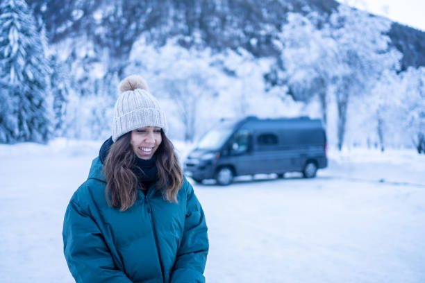 istock Young woman leaves vehicle on a snowy lake below mountains 1364510708