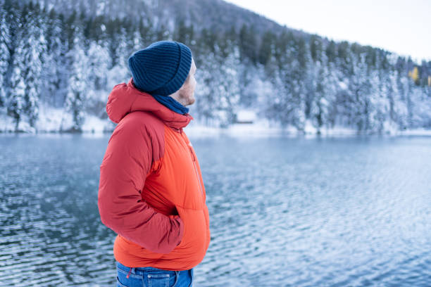 istock Young man pauses by lake and forest in winter 1364510847