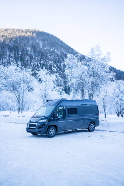 istock Camper-van parked in a snowy parking lot below mountains 1364512271