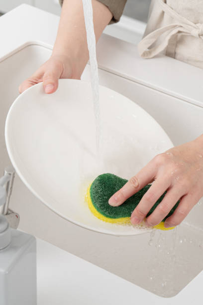 istock Woman housekeeper is doing the dishes at home kitchen. 1364518507