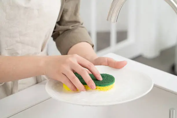 Close up of woman housewife is doing the dishes at home kitchen by using wash sponge and dishwashing.