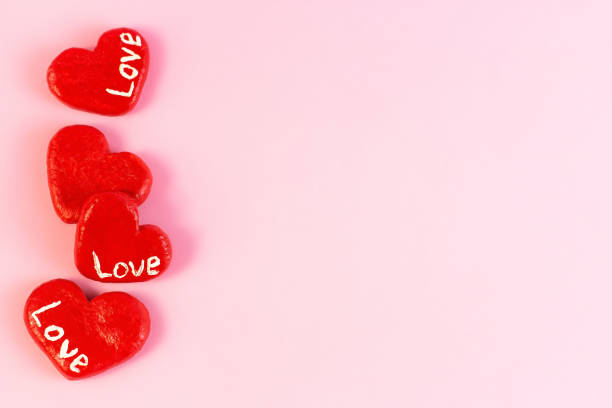 istock Bright red hearts decorations with Love words as a frame on light pink background with copy space. Valentines day celebration backdrop 1364523641