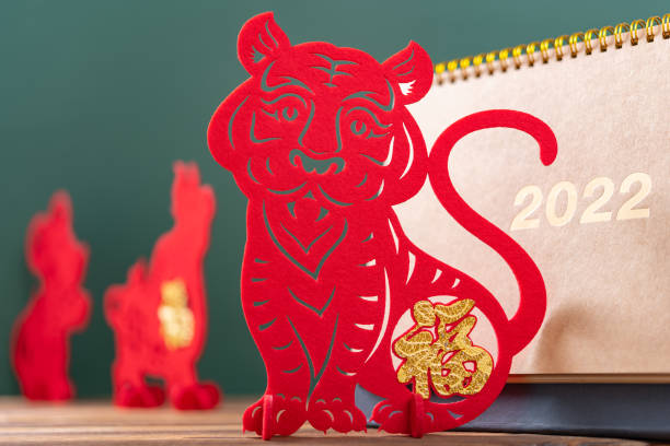 Chinese New Year of Tiger mascot paper cut and a 2022 calendar in front with Rat and Ox mascots at back, the Chinese means Happy New Year no logo no trademark stock photo