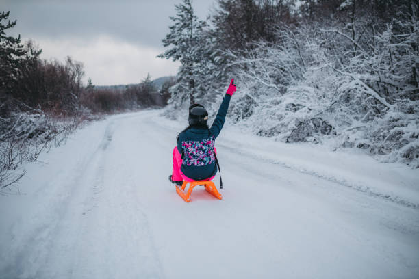 istock A young woman sleds downhill. 1364526755