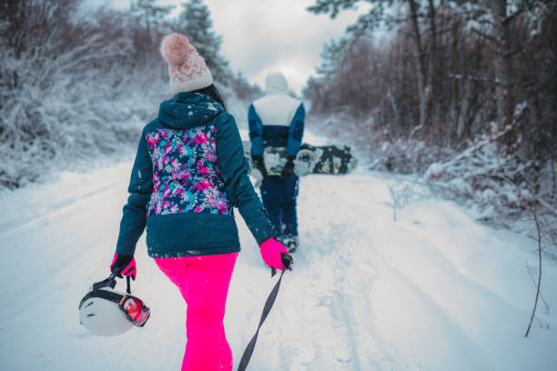 istock Two people with sled and snoboard in snowy landscape, rear view 1364529054