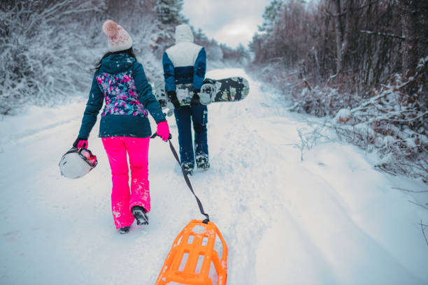 istock Two people with sled and snoboard in snowy landscape, rear view 1364529058