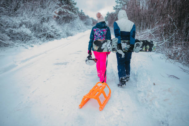 istock Two people with sled and snoboard in snowy landscape, rear view 1364529071