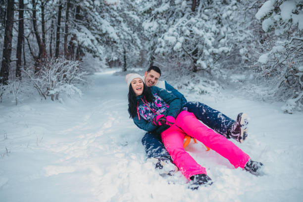 istock A happy couple enjoys a cold winter day while falling off a sled 1364530588