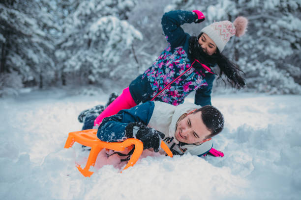 istock A happy couple enjoys a cold winter day while falling off a sled 1364530652