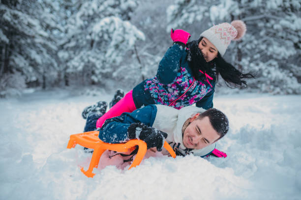 istock A happy couple enjoys a cold winter day while falling off a sled 1364530659