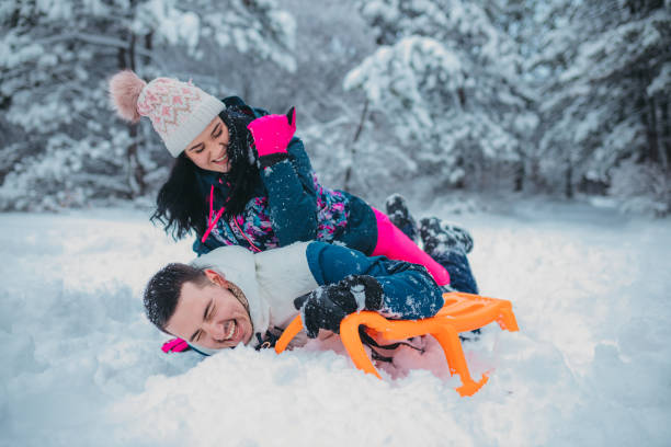 istock A happy couple enjoys a cold winter day while falling off a sled 1364530669