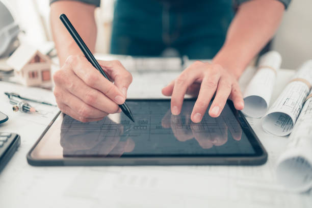 istock Architect engineer use tablet read and check drawing design working on bueprint. House planning design and construction concept. 1364535228