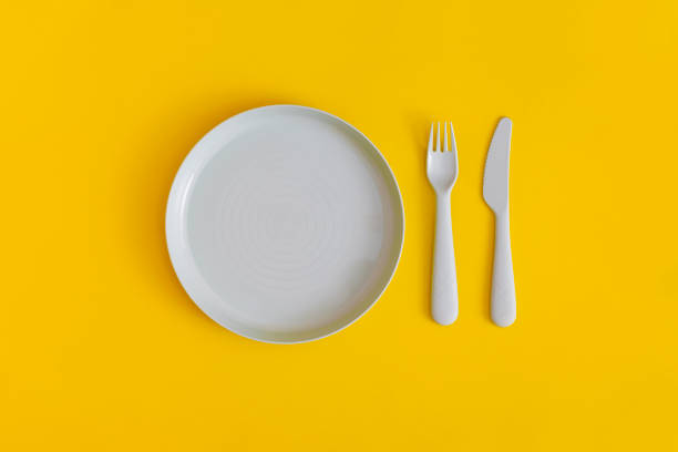 istock Blue plate with fork and spoon on a yellow background. Top view. Flat lay. 1364535662