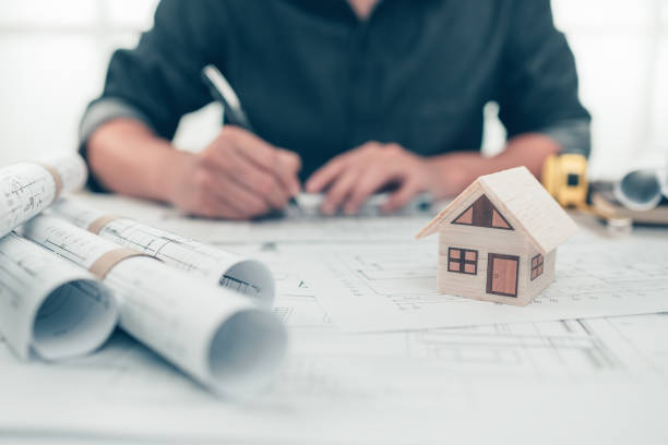 istock Mini model house, pencil, compass  and roll blueprint plan  on blueprint house plan design and architecture drawing. Architect and engineer concept. 1364536403
