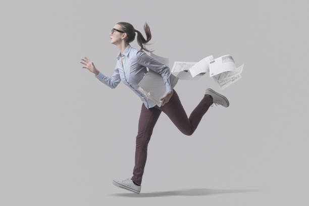Businesswoman running and losing paperwork stock photo