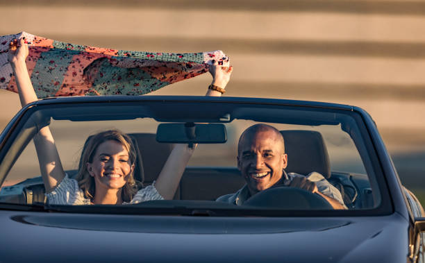 istock Happy couple having fun while going on a road trip by convertible car. 1364544790