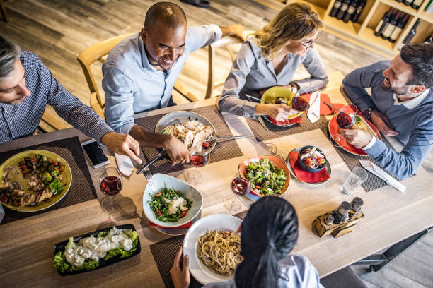 Above view of group of happy business people talking on a lunch. High angle view of happy business colleagues talking on a lunch break in a restaurant. business dinner stock pictures, royalty-free photos & images