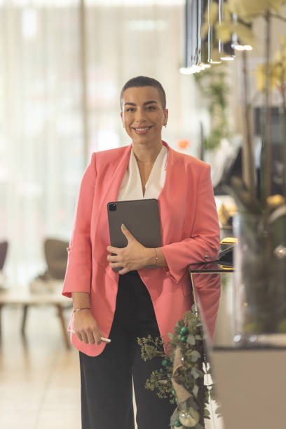 istock Short haired female receptionist standing in hotel lobby with tablet in hands 1364545641