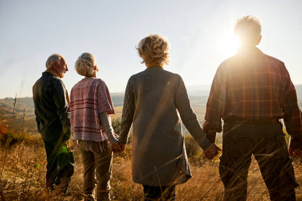 istock Back view of senior friends holding hands on a hill. 1364545992