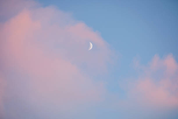 istock Half moon white on a blue sky with pink clouds 1364548121