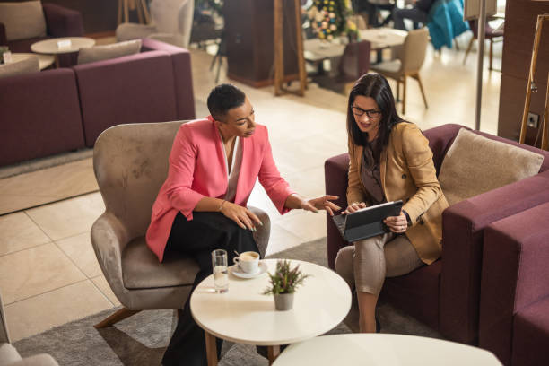 istock Two women sitting in hotel lobby and using tablet 1364549022