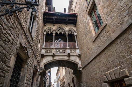 December 17, 2020. Barri Gotic, Barcelona, Catalonia, Spain.\n\nCarrer del Bisbe runs between Plaça de Sant Jaume and Cathedral Avenue in the Gothic Quarter area, the heart of old medieval Barcelona. It used to be attached to the Roman wall of Barcino until about the year 1250 the bishop of the city had that part of the wall demolished and the buildings that can be seen there were built.\nThe gallery bridge you see is part of the Casa dels Canonges, but despite its medieval appearance, it is actually an architectural medievalization carried out in the mid-1920s.