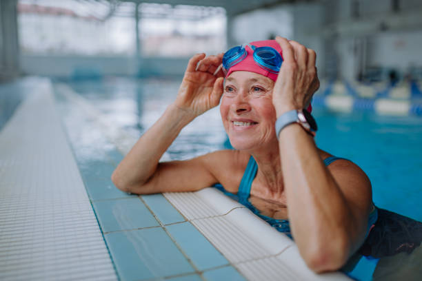 glückliche ältere frau im schwimmbad, auf kante gestützt. - lebensstil stock-fotos und bilder