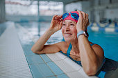 istock Happy senior woman in swimming pool, leaning on edge. 1364551940