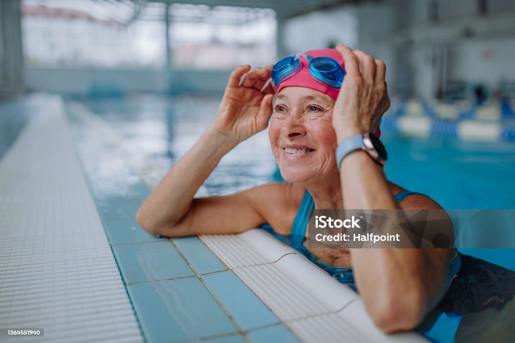 Happy senior woman in swimming pool, leaning on edge. A happy senior woman in swimming pool, leaning on edge. Senior Adult Stock Photo