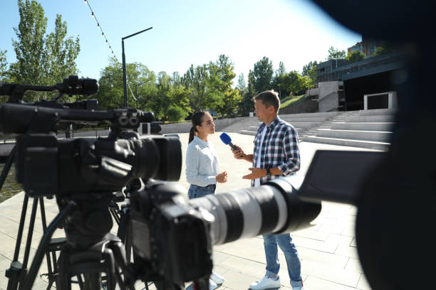 professioneller journalist interviewt junge frau auf der straße der stadt - photographer camera tripod paparazzi photographer stock-fotos und bilder