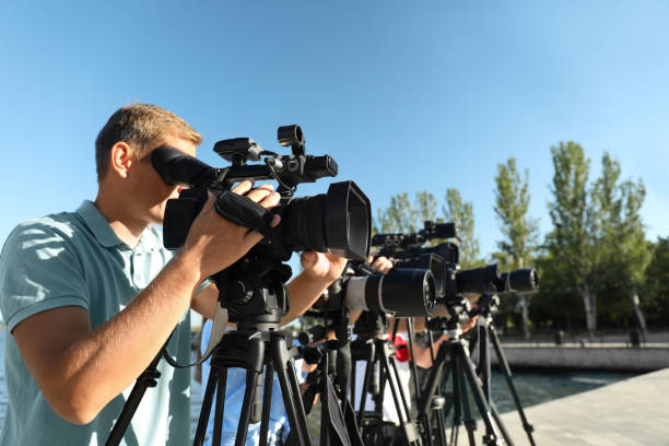istock Operators with professional video cameras working outdoors on sunny day 1364553898