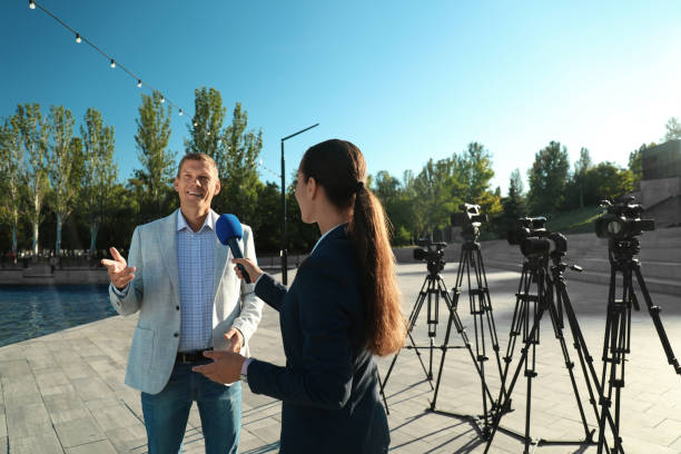 un jeune journaliste interviewant un homme d’affaires dans la rue de la ville - photographer camera tripod paparazzi photographer photos et images de collection