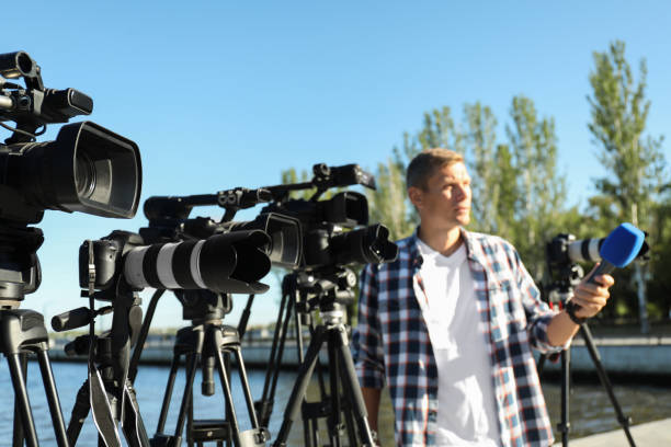 istock Professional journalist with microphone working outdoors, focus on video cameras 1364553902