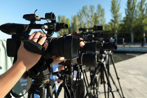 istock Operators with professional video cameras working outdoors on sunny day, closeup 1364554343