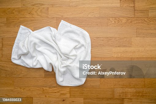 istock Used white towel lying on wooden floor at a hotel room 1364555023