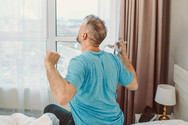 istock Happy rested man with chronic breathing issues after using  CPAP machine sitting on the bed in bedroom. 1364555170