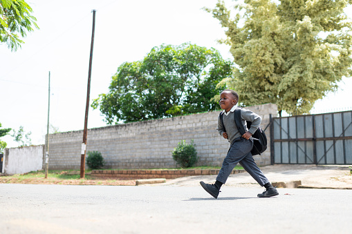 Confident young schoolboy crosses the street