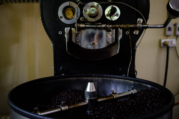 fresh coffee beans - chicchi di caffè 100% qualità arabica tostati che cadono in una macchina frigorifera professionale rotante. presso l'industria comunitaria chiang rai tailandia - roasted machine bean mixing foto e immagini stock