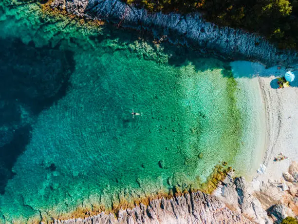 overhead view of woman floating on back in clear sea water greece vacation