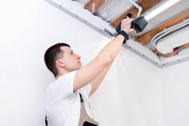 istock man makes home repairs. Preparing to install a stretch ceiling. 1364557577