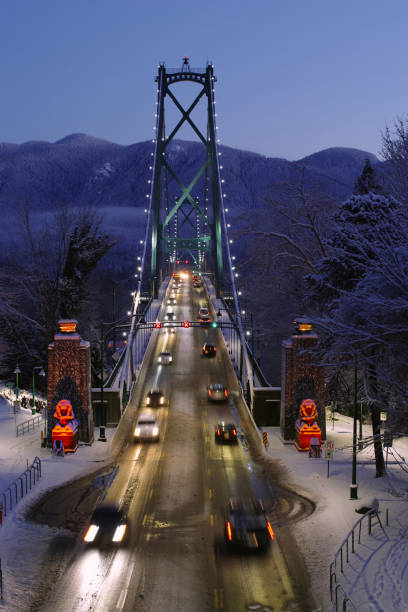 Entrance to Vanouver Lions Gate Bridge on a rare Snow storm. Grouse Mountain in the background, Bridge guarded by the two lion Statues at the entrance. . west vancouver stock pictures, royalty-free photos & images