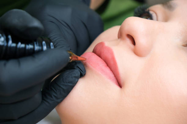 istock Young woman having permanent makeup on her lips at the beauticians salon. 1364561292