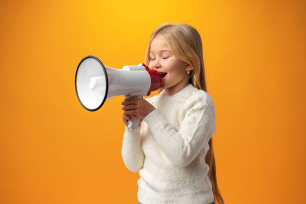 istock Child girl using megaphone against yellow background 1364561470