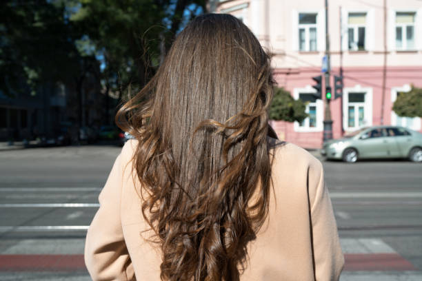 Woman with long dark hair crosses the road stock photo