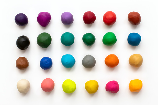 Piezas o bolas de arcilla de modelado de plastilina colorida aislada sobre fondo blanco. Vista superior con sombra. Concepto de juguetes infantiles creativos. Juego de 24 colores. photo