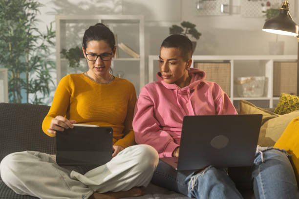 istock Two friends sitting on sofa while looking something on laptop 1364571131