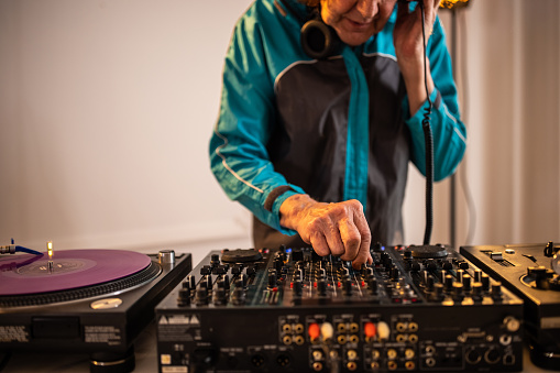 Unrecognizable Caucasian senior man with cool attitude, an DJ, performing the music set
